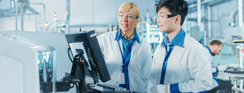 A male and female scientist standing a computer in a lab talking